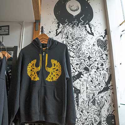 A gray sweatshirt hangs on a rack in front of a painted wall at Town Biz in Oakland, California