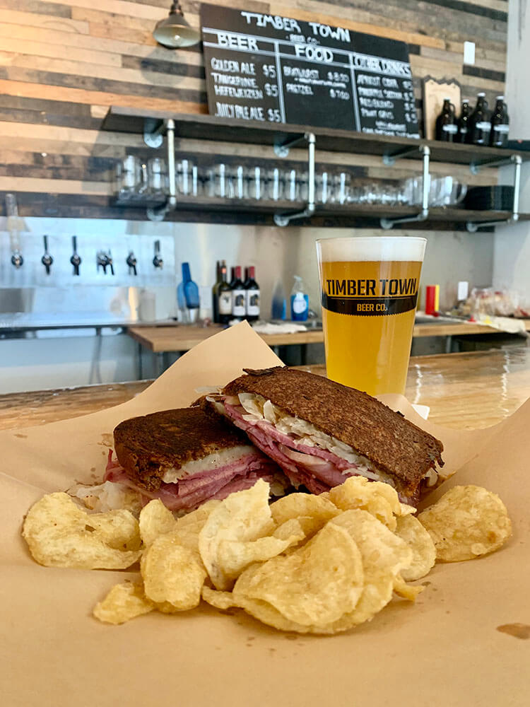 a pint gass of Tangerine Hefeweizen with a reuben sandwich. 