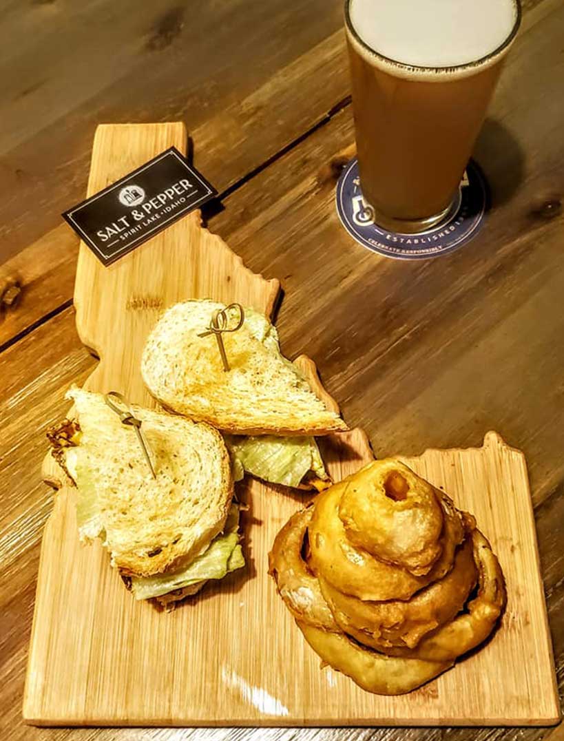 overview shot of an Idaho shaped board with a sandwich and a pint of beer