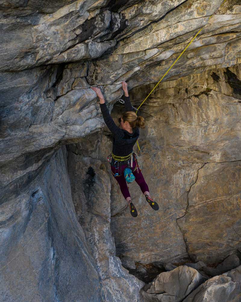 a woman hangs from a natural rock wall while rock climbing 