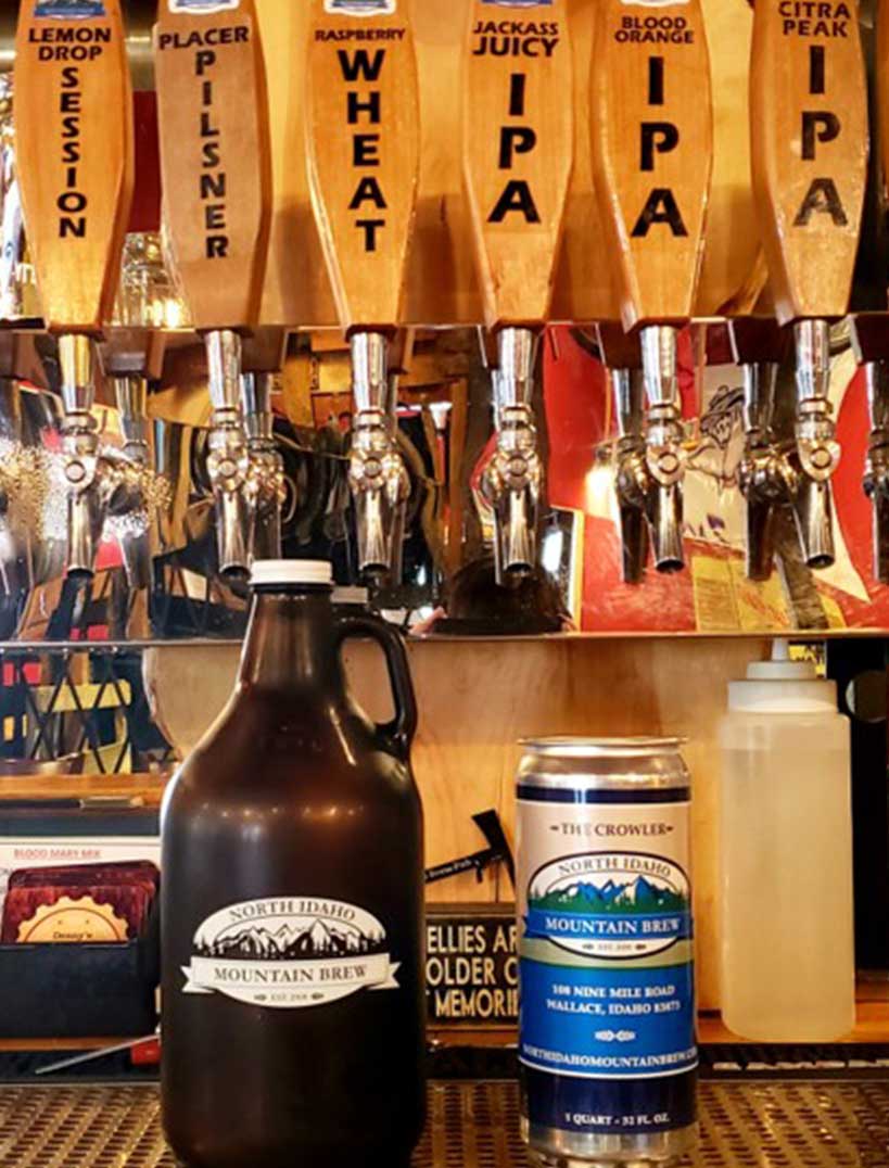 A beer can and growler sit in front of wooden beer taps
				