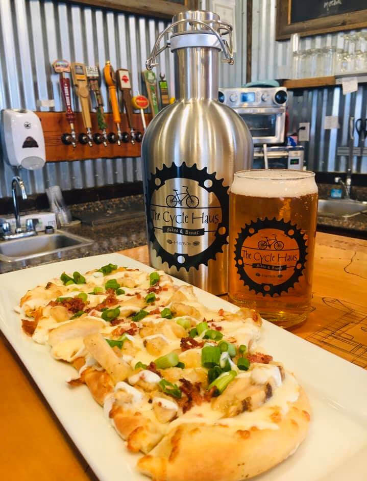 flatbread pizza infront of pint of beer and a growler 